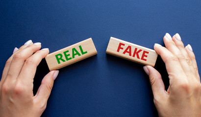 Real or Fake symbol. Concept word Real or Fake on wooden blocks. Businessman hand. Beautiful deep...