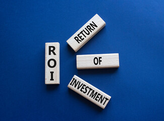 ROI - Return of Investment. Wooden cubes with words ROI. Beautiful deep blue background. Business and ROI concept. Copy space.