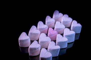 Marshmallow hearts for Valentine's Day on black glass. Soft selective focus.
