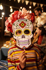 Vertical portrait of little girl in skull mask looking at camera during celebration of holiday