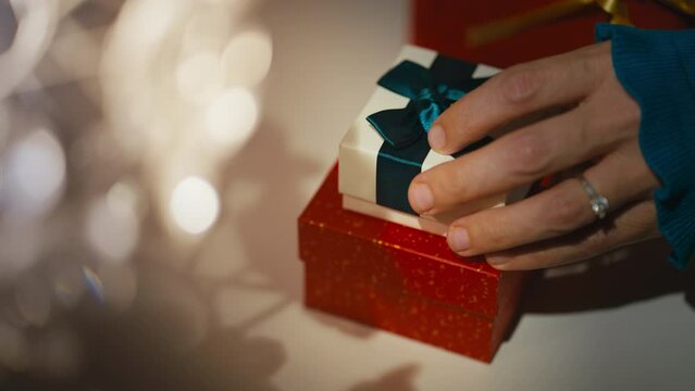 Female Hand Puts Jewelry Gift Box on Red Gift Box