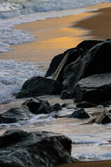 Unas piedras en la orilla del mar con los reflejos anaranjados del sol al atardecer