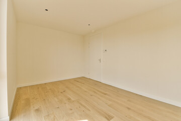 an empty room with white walls and wood flooring on the right side of the room, there is a door in the corner