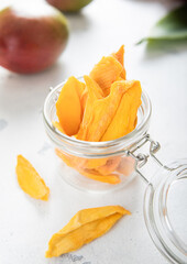Sweet dried mango slices with fresh raw fruits on light background.