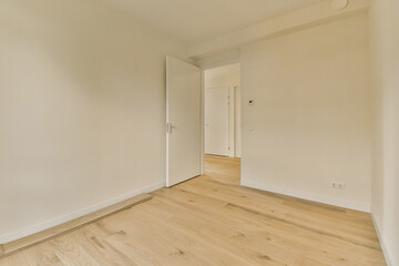 an empty room with white walls and wood flooring on the right, there is a door that leads to another room