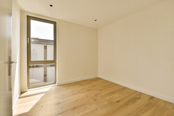 an empty room with wood flooring and sliding glass door that leads to the balcony area in the apartment building