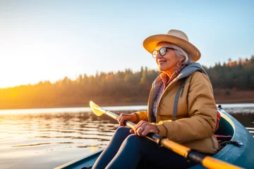 Foto op Canvas Retired older woman enjoying a peaceful moment while canoeing or kayaking on calm waters during late afternoon or dusk. A serene scene, contemplative solitude and tranquility © MVProductions