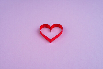 Top view Valentine's Day concept with copy space. Red ribbon heart on purple papper background