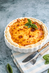 Quiche. Homemade cheese tart  or quiche with cheese, pecorino, bacon and spinach on gray concrete light table background. French Quiche. Top view.