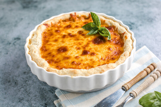 Quiche. Homemade cheese tart  or quiche with cheese, pecorino, bacon and spinach on gray concrete light table background. French Quiche. Top view.