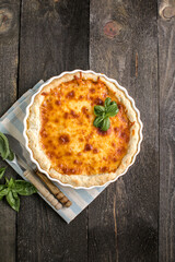 Quiche. Homemade cheese tart  or quiche with cheese, pecorino, bacon and spinach on gray concrete light table background. French Quiche. Top view.