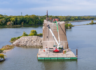 Heavy machinery removes the concrete pillars of historic I-74 bridge between Bettendorf Iowa and...