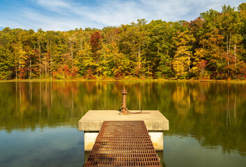 Changing leaves in autumn with metal walkway and platform in calm reservoir in Coopers Rock State...