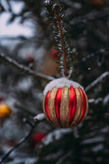 Obraz premium Snow-covered Christmas trees with red balloons and garlands on the city street. Decoration of the city for the New Year. Snow-covered New Year's streets of the city