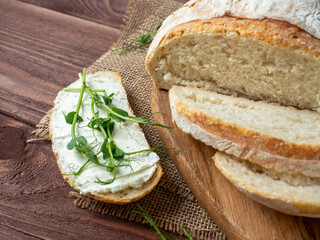 Close-up of a still life made of fresh crusty bread. A slice of bread smeared with cottage cheese...
