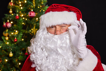 Santa Claus adjusts his glasses and winks with one eye