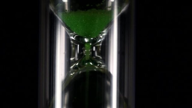 Hourglass with green flowing sand. Time is running out in the hourglass. Time is over. The sand is gone