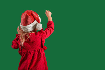 a Girl in santa claus hat draws christmas drawing on the blackboard