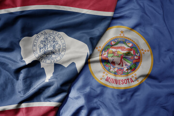 big waving colorful national flag of minnesota state and flag of wyoming state .