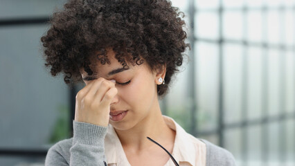 woman in the office is tired of working on the computer. took off her glasses and rubs her eyes