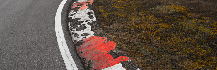 Roadside stripes, red and white, of an old crumbling race track