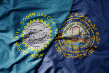 big waving colorful national flag of new hampshire state and flag of south dakota state.