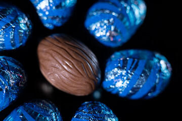 Chocolate eggs with and without paper. Black background. Easter eggs.
