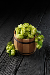 Hops in a wooden keg on a black wooden background