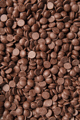 Chocolate drops for making chocolate, candy as a background, macro photo. Chocolate background.