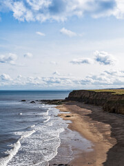 Fototapeta na wymiar Beach and cliffs with cloud, horizon and sea, Sunderland, UK