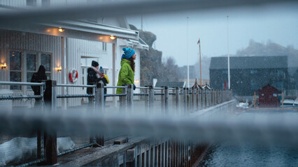 Lofoten islands, Senja region, Norway. Winter. Fishing town. Young girl in green jacket and blue...