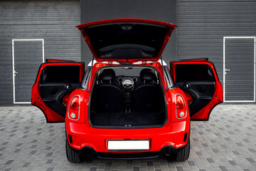 Compact, stylish and youthful crossover in bright red color. Modern black car interior.  Details...