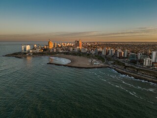 a city and its beach as the sun sets on the horizon