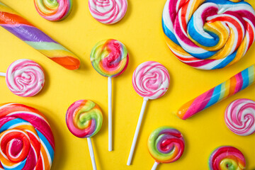 Various lollipops in bright and bold colours on a yellow background