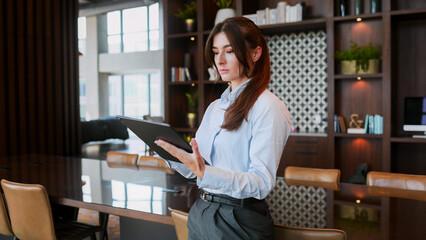 Portrait of elegant gorgeous successful businesswoman using tablet and standing in company office...