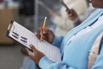 Hand of young female applicant with pencil pointing at filled form while checking personal information before passing documents to manager