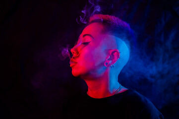 Profile Asian woman with short haircut smoking in neon light.
