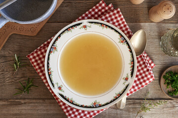 Chicken soup or bone broth in plate on a table
