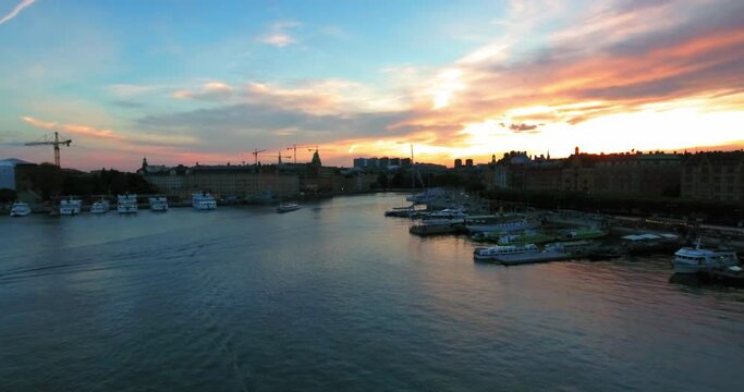 Aerial Forward Shot Of Ferries On Sea By Buildings In City During Sunset Against Sky - Stockholm, Sweden