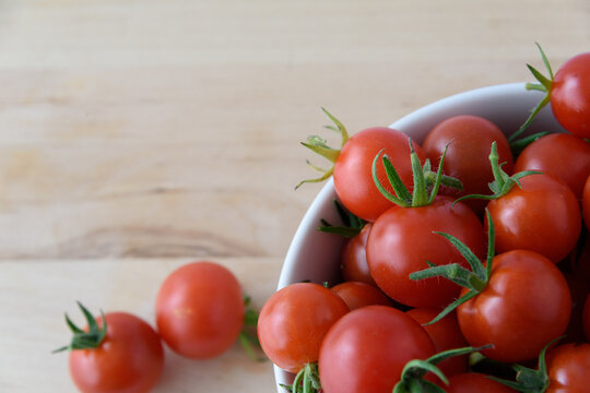 tomatoes in a white bowl on a wooden table in flatlay with empty space