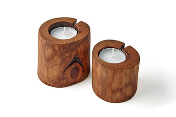 Two candles in wooden candlesticks from a tree trunk with a crack isolated on a white background