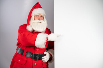 Santa claus points to an empty space. Christmas advertisement.