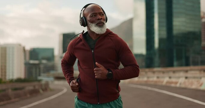 Senior, fitness and black man running in a city street with music headphones, podcast or energy. Workout, training and elderly African male runner with radio earphones in a road for cardio exercise