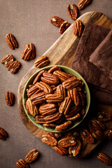 Obraz na płótnie Canvas Pecan nuts in a bowl on a brown background, top view