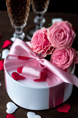 Beautiful surprise greeting for saint Valentine's or Women's Day, birthday or Anniversary for beloved. Fresh pink roses, gift box with sweets. Dark background. Holiday atmosphere