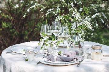 Rustic zero waste wedding decor with natural elements. Fresh spring blooming flowers, candles, linen napkins, wine glasses. Eco friendly decoration for the special holiday dinner. Romantic cozy place