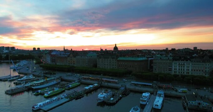 Aerial Backward Shot Of Ferries Near Promenade During Sunset In City - Stockholm, Sweden
