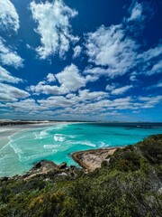 Beautiful view of blue ocean water waves in a sandy beach with blue cloudy sky