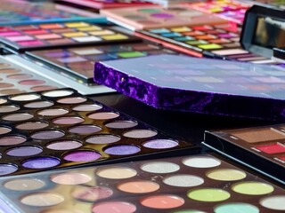 Closeup of many colorful makeup palettes with mirrors on a table