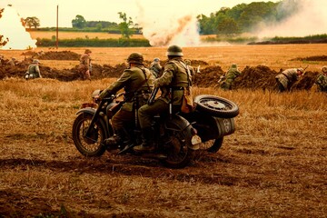 Two dispatch riders riding a motorcycle on a battle during a war